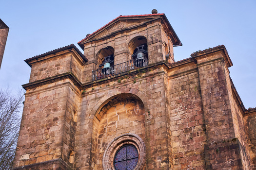 Pasai Donibane Spain 09 March 2026 View of the historic stone facade and bell tower of a traditional church under a clear blue sky.