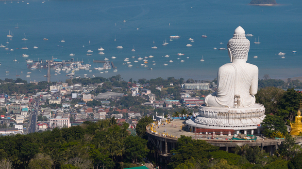 Aerial view of Big Buddha Phuket statue overlooking the bay with numerous boats urban buildings and lush green trees Karon Phuket Thailand. Aerial view of Big Buddha Phuket statue overlooking the bay with numerous boats urban buildings and lush green trees Karon Phuket Thailand.