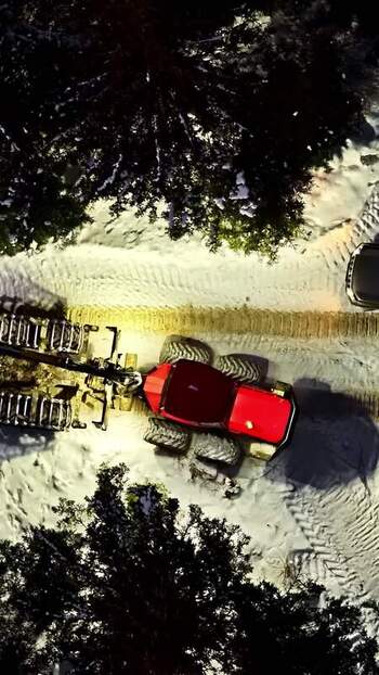 Aerial view of a red tractor working in a snowy forest Latvia.