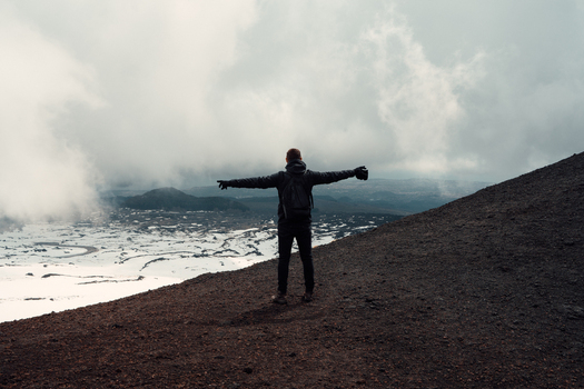 View of a lone figure standing atop a ridge arms outstretched overlooking a snow dusted landscape shrouded in mist Taormina Sicily Italy. View of a lone figure standing atop a ridge arms outstretched overlooking a snow dusted landscape shrouded in mist Taormina Sicily Italy.