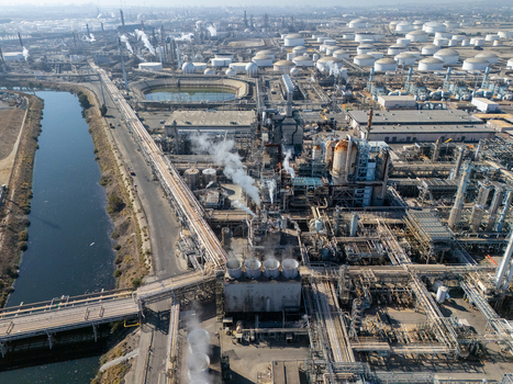 Aerial view of an industrial oil refinery complex with storage tanks processing units and a canal in Carson California United States.