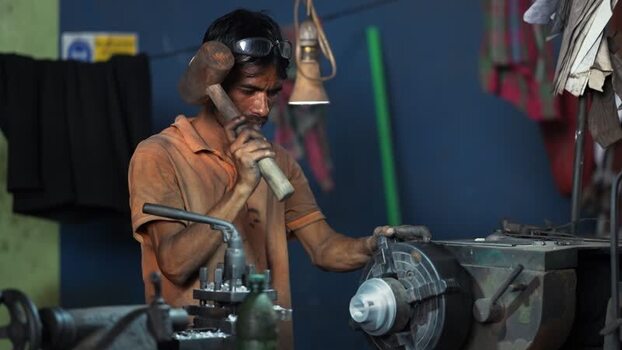View of a worker using a wooden mallet in a workshop Bangladesh.