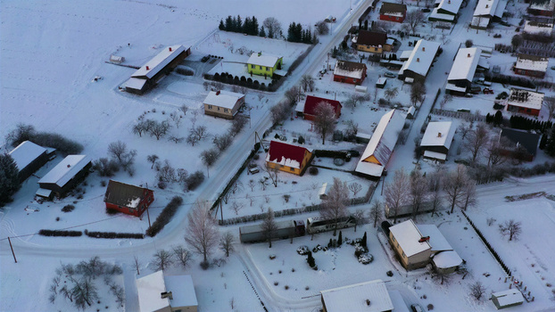 Aerial view of a small village with colorful houses and snow covered rooftops surrounded by snowy fields and trees in LATVIJA. Aerial view of a small village with colorful houses and snow covered rooftops surrounded by snowy fields and trees in LATVIJA.