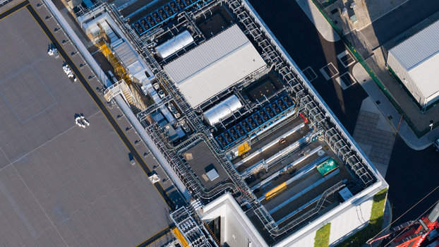 Aerial view of the industrial roof of a data center facility featuring numerous cooling units ventilation systems and complex piping in Longcross England United Kingdom.