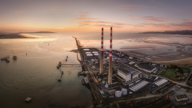 Aerial view of Poolbeg Power Station with its iconic red and white chimneys overlooking Dublin Bay during a vibrant sunset with industrial structures and calm coastal waters Dublin 4 County Dublin Ireland. Aerial view of Poolbeg Power Station with its iconic red and white chimneys overlooking Dublin Bay during a vibrant sunset with industrial structures and calm coastal waters Dublin 4 County Dublin Ireland.