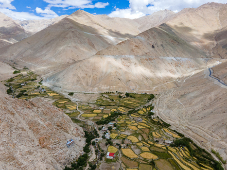 Aerial view of terraced fields and a small village nestled among the arid mountain slopes of the Himalayas in Ladakh Division Ladakh India. Aerial view of terraced fields and a small village nestled among the arid mountain slopes of the Himalayas in Ladakh Division Ladakh India.