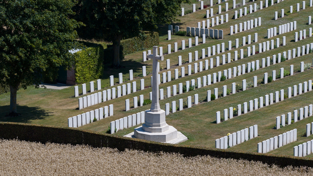 Aerial view of Delville Wood Cemetery featuring rows of white headstones and a central Cross of Sacrifice set within manicured lawns in Longueval Hauts de France France.