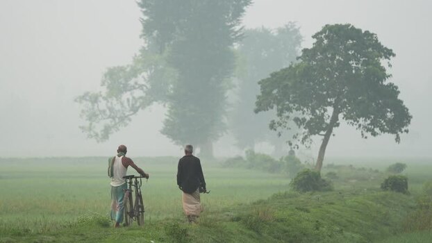 View of two men walking through a misty rural landscape Bangladesh.