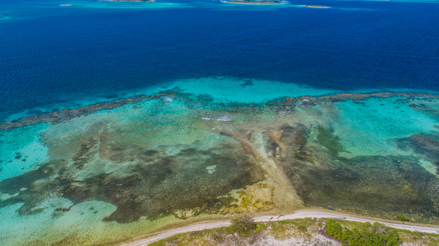 Aerial view of Los Roques archipelago featuring vibrant turquoise coral reefs shallow crystal clear waters and a sandy coastline in Los Roques Dependencias Federales Venezuela. Aerial view of Los Roques archipelago featuring vibrant turquoise coral reefs shallow crystal clear waters and a sandy coastline in Los Roques Dependencias Federales Venezuela.