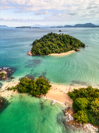 Aerial view of Ilha Cataguas with lush green vegetation white sandy beaches turquoise waters and a small boat anchored near the shore in Rio de Janeiro Brazil. Aerial view of Ilha Cataguas with lush green vegetation white sandy beaches turquoise waters and a small boat anchored near the shore in Rio de Janeiro Brazil.
