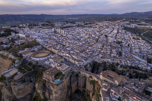 Aerial view of the historic town of Ronda featuring the iconic Puente Nuevo bridge spanning the El Tajo gorge the bullring and white washed buildings in Ronda Andalusia Spain. Aerial view of the historic town of Ronda featuring the iconic Puente Nuevo bridge spanning the El Tajo gorge the bullring and white washed buildings in Ronda Andalusia Spain.