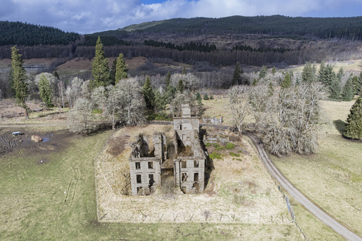 Aerial view of the ruins of Guisachan Historic House surrounded by trees and grassy fields in Beauly Glen Affric Scotland United Kingdom. Aerial view of the ruins of Guisachan Historic House surrounded by trees and grassy fields in Beauly Glen Affric Scotland United Kingdom.
