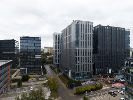 Aerial view of a modern business park featuring glass and steel office buildings parking lots and surrounding greenery in Krakow Lesser Poland Voivode Poland.