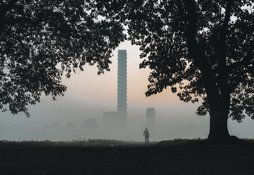 View of a solitary figure stands amidst the ethereal morning mist framed by the dark silhouettes of trees with the city s tall buildings fading into the horizon Kolkata West Bengal India. View of a solitary figure stands amidst the ethereal morning mist framed by the dark silhouettes of trees with the city s tall buildings fading into the horizon Kolkata West Bengal India.