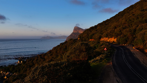 Aerial view of the winding Chapman s Peak Drive coastal road along steep green hillsides overlooking the Atlantic Ocean at sunset Cape Town Western Cape South Africa. Aerial view of the winding Chapman s Peak Drive coastal road along steep green hillsides overlooking the Atlantic Ocean at sunset Cape Town Western Cape South Africa.
