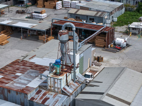 Melbourne VIC Australia 25 September 2026 Aerial view of industrial factory site featuring wood stacks metal machinery and corrugated iron rooftops.