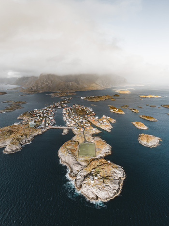 Aerial view of the Lofoten archipelago featuring the iconic football pitch in Henningsvaer surrounded by rocky islands and coastal waters in Leknes Nordland Norway. Aerial view of the Lofoten archipelago featuring the iconic football pitch in Henningsvaer surrounded by rocky islands and coastal waters in Leknes Nordland Norway.