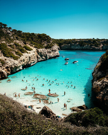 Mallorca Spain 15 September 2023 View of Cala des Moro with turquoise water rocky cliffs and people swimming and relaxing on the beach under a clear blue sky. Mallorca Spain 15 September 2023 View of Cala des Moro with turquoise water rocky cliffs and people swimming and relaxing on the beach under a clear blue sky.