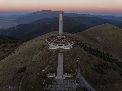 Aerial view of Buzludzha Monument a brutalist structure atop a mountain peak during golden hour with rolling hills and distant mountains Stara Zagora Bulgaria. Aerial view of Buzludzha Monument a brutalist structure atop a mountain peak during golden hour with rolling hills and distant mountains Stara Zagora Bulgaria.