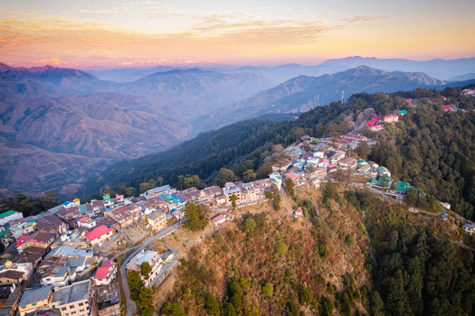 Aerial view of the colorful buildings of Chakrata hill station perched on a mountain ridge during sunset with distant Himalayan peaks in Chakrata Uttarakhand India. Aerial view of the colorful buildings of Chakrata hill station perched on a mountain ridge during sunset with distant Himalayan peaks in Chakrata Uttarakhand India.