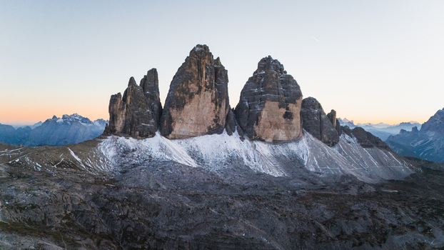 Aerial view of the iconic Tre Cime di Lavaredo mountain peaks with snow dusted slopes under a soft twilight sky in Auronzo di Cadore Veneto Italy. Aerial view of the iconic Tre Cime di Lavaredo mountain peaks with snow dusted slopes under a soft twilight sky in Auronzo di Cadore Veneto Italy.