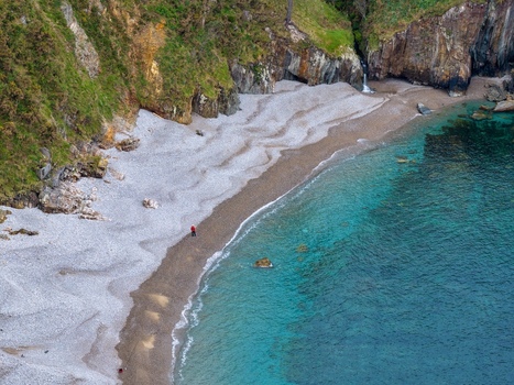 Aerial view of the secluded Playa del Silencio with its turquoise waters pebble shore and steep green cliffs in Cudillero Asturias Spain.