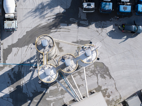 Aerial view of the Holcim concrete plant featuring large industrial silos and parked trucks on a paved yard in Krakow Lesser Poland Voivode Poland.