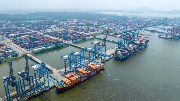 Aerial view of Jawaharlal Nehru Port Authority with large container ships being loaded by cranes extensive container stacks and industrial infrastructure in Juna Sheva Maharashtra India. Aerial view of Jawaharlal Nehru Port Authority with large container ships being loaded by cranes extensive container stacks and industrial infrastructure in Juna Sheva Maharashtra India.