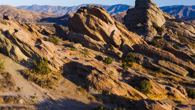 Aerial view of the rugged sandstone rock formations at Vasquez Rocks featuring dramatic geological layers desert vegetation and long shadows cast during the golden hour in the United States. Aerial view of the rugged sandstone rock formations at Vasquez Rocks featuring dramatic geological layers desert vegetation and long shadows cast during the golden hour in the United States.