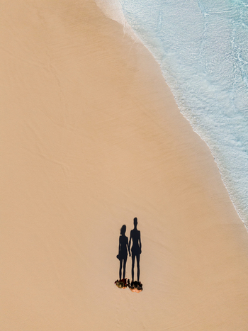 Aerial view of the shadows of a couple standing on the white sand beach at Lucky Bay with turquoise ocean waves nearby in Cape Le Grand National Park Western Australia Australia. Aerial view of the shadows of a couple standing on the white sand beach at Lucky Bay with turquoise ocean waves nearby in Cape Le Grand National Park Western Australia Australia.