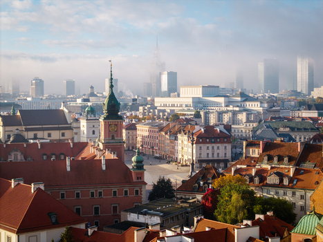 Aerial view of the Royal Castle and historic red roofed buildings in the old town of Warsaw with modern skyscrapers shrouded in morning mist Poland. Aerial view of the Royal Castle and historic red roofed buildings in the old town of Warsaw with modern skyscrapers shrouded in morning mist Poland.