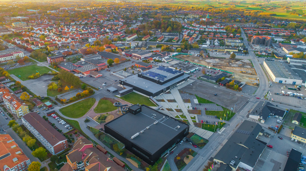 Aerial view of a modern black building complex with a water slide surrounded by parking areas residential houses and autumn trees in a town in Sweden. Aerial view of a modern black building complex with a water slide surrounded by parking areas residential houses and autumn trees in a town in Sweden.