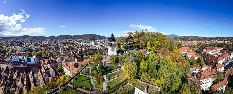 Aerial view of the clock tower the Schlossberg hill and the cityscape under a clear blue sky Graz Styria Austria.