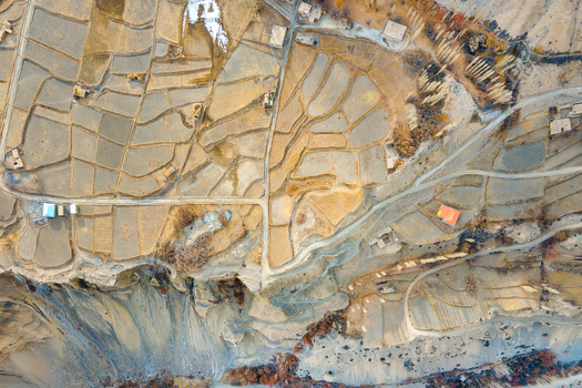 Aerial view of golden terraces meeting rugged cliffs under a soft ethereal light in Chapursan Valley Hunza Nagar Gilgit Pakistan. Aerial view of golden terraces meeting rugged cliffs under a soft ethereal light in Chapursan Valley Hunza Nagar Gilgit Pakistan.