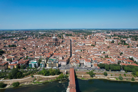 Aerial view of the historic city center with the Ponte Coperto bridge over the Ticino river and the Duomo di Pavia under a clear blue sky in Pavia Lombardy Italy. Aerial view of the historic city center with the Ponte Coperto bridge over the Ticino river and the Duomo di Pavia under a clear blue sky in Pavia Lombardy Italy.