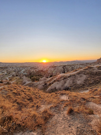 View of the unique rock formations and fairy chimneys under a golden sunset sky in Cappadocia Turkiye. View of the unique rock formations and fairy chimneys under a golden sunset sky in Cappadocia Turkiye.