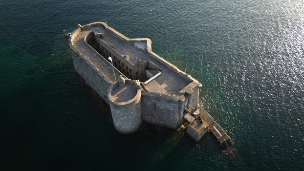 Aerial view of Chateau du Taureau a stone fortress rising from the dark water its stark silhouette contrasting with the shimmering surface Plouezoc h Bretagne France. Aerial view of Chateau du Taureau a stone fortress rising from the dark water its stark silhouette contrasting with the shimmering surface Plouezoc h Bretagne France.