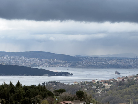 View of the Bosphorus strait with a cargo ship navigating the water under dark storm clouds in Sariyer Istanbul Turkiye.