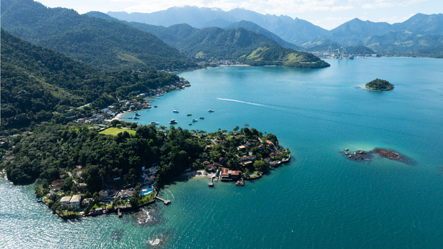 Aerial view of Ilha de Cataguas surrounded by turquoise waters lush green hills and coastal houses in Angra dos Reis State of Rio de Janeiro Brazil.