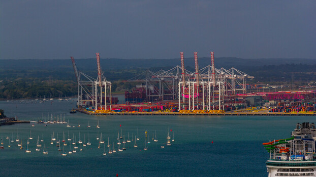 Aerial view of the busy Port of Southampton container terminal with large cranes cargo ships and numerous sailboats moored in the bay Southampton England United Kingdom. Aerial view of the busy Port of Southampton container terminal with large cranes cargo ships and numerous sailboats moored in the bay Southampton England United Kingdom.