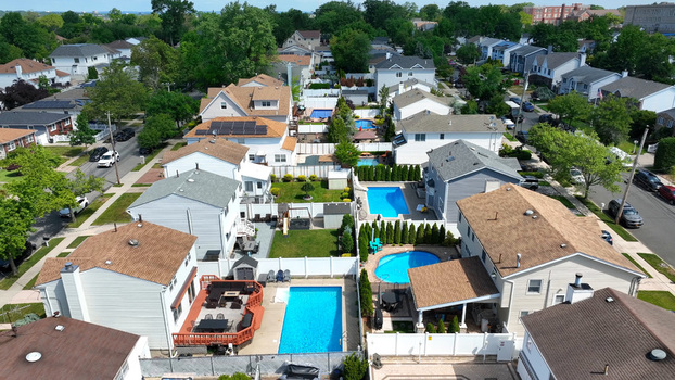 Aerial view of residential neighborhood in Tottenville Staten Island featuring houses with swimming pools green lawns and suburban streets in New York New York United States. Aerial view of residential neighborhood in Tottenville Staten Island featuring houses with swimming pools green lawns and suburban streets in New York New York United States.
