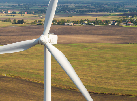 Aerial view of a white wind turbine standing in vast agricultural fields in Pomeranian Voivodeship Poland. Aerial view of a white wind turbine standing in vast agricultural fields in Pomeranian Voivodeship Poland.