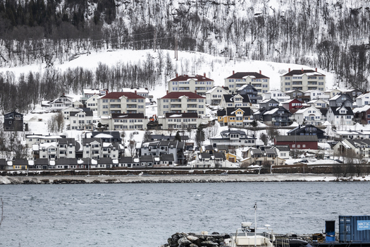 View of colorful houses and apartment buildings on a snowy hillside overlooking the water Tromso Troms Norway. View of colorful houses and apartment buildings on a snowy hillside overlooking the water Tromso Troms Norway.
