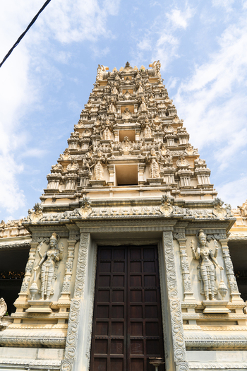 View of the ornate gopuram of a Hindu temple featuring intricate carvings of deities under a bright sky in Galle Southern Province Sri Lanka.