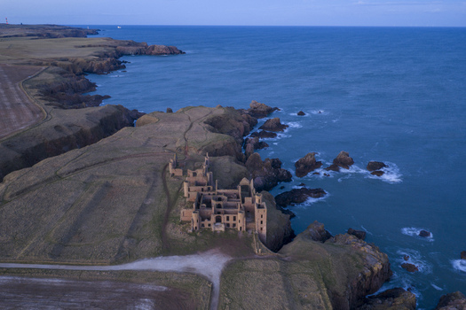 Aerial view of the ruined Slains Castle Dracula s Castle on the edge of dramatic cliffs overlooking the North Sea at twilight Cruden Bay Scotland United Kingdom. Aerial view of the ruined Slains Castle Dracula s Castle on the edge of dramatic cliffs overlooking the North Sea at twilight Cruden Bay Scotland United Kingdom.