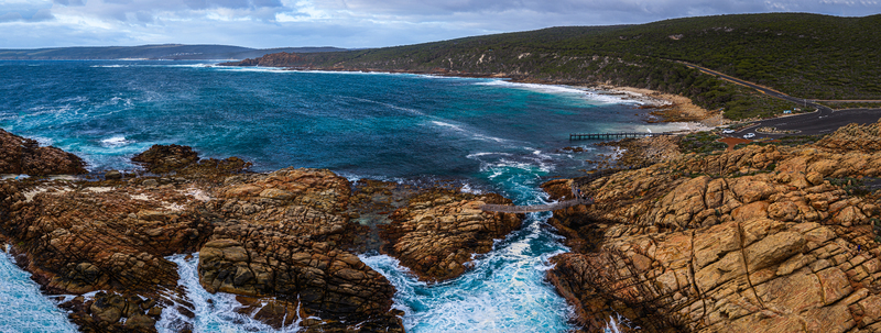 Aerial view of Canal Rocks Bridge with rugged granite rock formations turquoise ocean waves crashing against the shore and a coastal road in Yallingup Western Australia Australia.