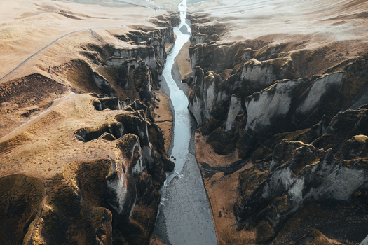 Aerial view of a winding river cutting through a deep canyon with contrasting light and shadow Fjadrargljufur Iceland. Aerial view of a winding river cutting through a deep canyon with contrasting light and shadow Fjadrargljufur Iceland.