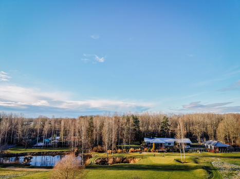 Valmiera Valmiera Latvija 18 November 2025 Aerial view of a golf course featuring a clubhouse a small pond and surrounding birch trees on a frosty morning.