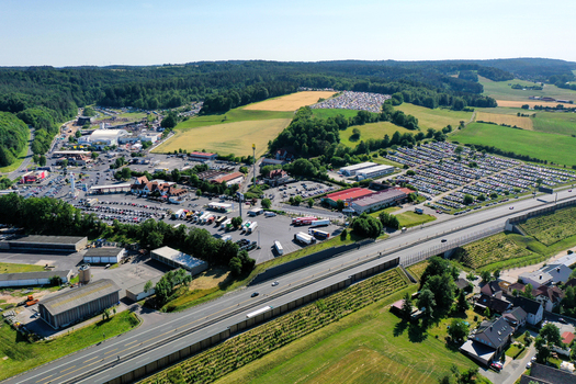 Geiselwind Germany 21 June 2025 Aerial view of Eventzentrum Strohofer Geiselwind musichall with extensive parking lots and the highway surrounded by green fields and forests. Geiselwind Germany 21 June 2025 Aerial view of Eventzentrum Strohofer Geiselwind musichall with extensive parking lots and the highway surrounded by green fields and forests.