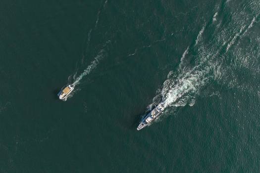 Aerial view of two boats navigating the dark waters of Lake Como leaving white wakes behind them in Como Lombardy Italy.